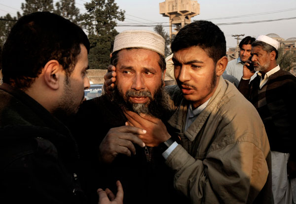 People comfort a man who lost a family member in a suicide attack in Mardan, Pakistan, onTuesday (AP photo)