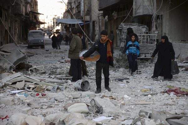 A youth carries a tray of traditional sweets in a site damaged from what activists said was shelling by forces loyal to Syria's President Bashar Assad in the town of Douma, eastern Ghouta in Damascus, on Wednesday (AFP photo)