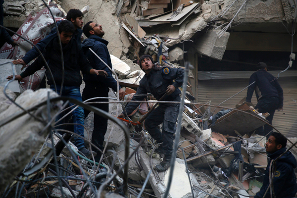 Syrians and civil defence workers search for victims amid the rubble of a destroyed building following air strikes on the Eastern Ghouta town of Douma, a rebel stronghold east of the capital Damascus, on Sunday (AFP photo)