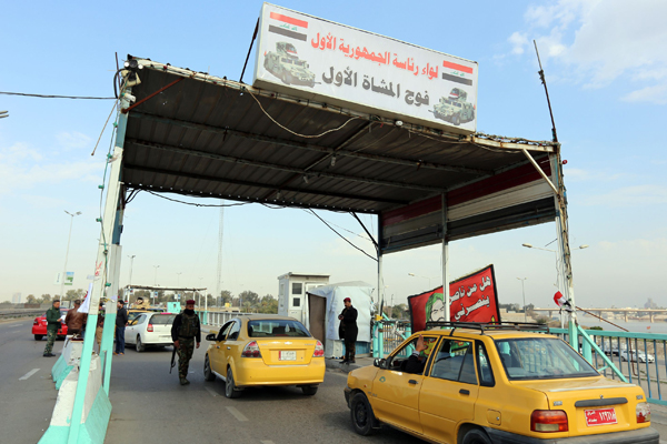 Iraqi security forces inspect a car at a checkpoint on the main road from Baghdad’s central Jaderiyah district to Dora on the southern outskirts of the Iraqi capital on Monday (AFP photo)