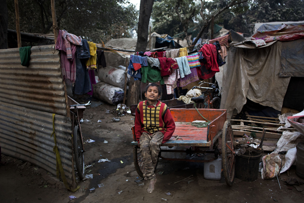 An Indian boy sits on a cart in a slum area, New Delhi, India, Monday (AP photo)