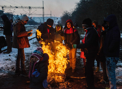 Migrants and refugees keep warm around a bonfire waiting at a train station for a train in the  southern Serbian town of Presevo, on Wednesday (AFP photo)