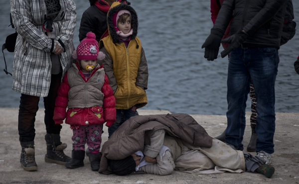 In this photo taken on Wednesday, an elderly woman lies on the dock as she waits to be transferred to a nearby island after she arrived with others from Turkey to the deserted island of Papas , near Chios Island (AP photo)