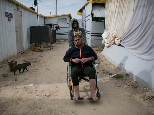 Samir Al Najjar sits on a wheelchair next to his prefabricated metal home in the southern Gaza Strip town of Khan Younis on Sunday (AFP photo)