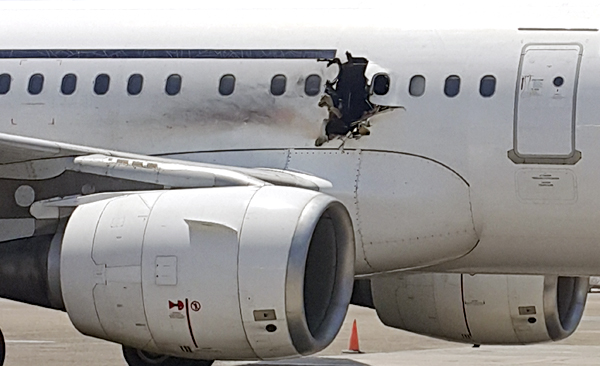 In this Tuesday photo, a hole is photographed in a plane operated by Daallo Airlines as it sits on the runway of the airport in Mogadishu, Somalia (AP photo)