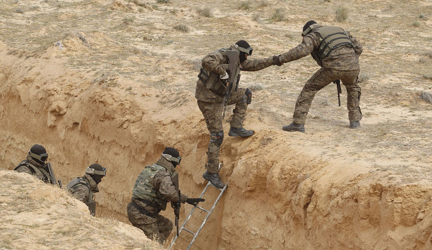 Tunisian soldiers participating in an exercise climb out of a trench that forms part of a barrier along the frontier with Libya in Sabkeht Alyun, on Saturday (Reuters photo)