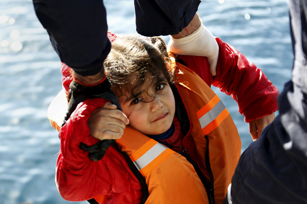 Greek coast guard officers move a girl from a dinghy carrying refugees and migrants aboard the Ayios Efstratios coast guard vessel,  during a rescue operation at open sea between the Turkish coast and the Greek island of Lesbos, on Monday (Reuters photo)