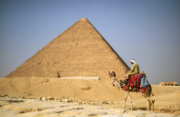 An Egyptian man rides a camel in front of one of the Giza pyramids in the southern Cairo Giza district on January 20, 2016 (AFP photo)