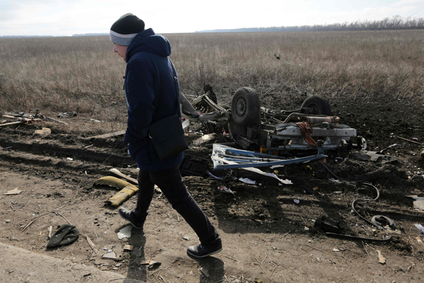 A man walks past the debris of a passenger minibus after it hit a mine near Marinka on Wednesday (AFP photo)