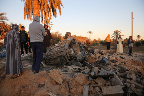 In this Friday photo, people gather after an air strike on a house and training camp belonging to the Daesh group, west of Sabratha (AP photo)