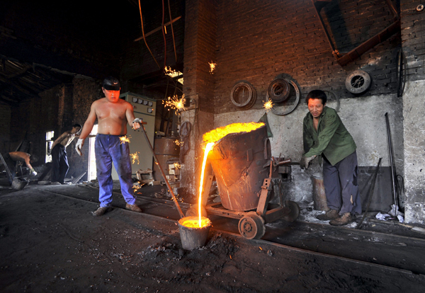Labourers pour molten iron into a container at a foundry in Xiangfan, Hubei province, in this July 2, 2010 file photo (Reuters photo)