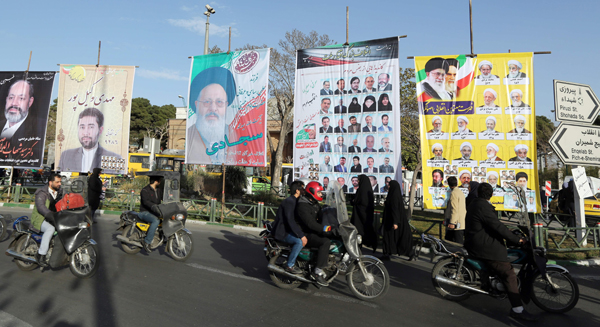 Iranians ride past campaign posters for upcoming parliamentary elections in downtown Tehran, on Tuesday (AFP photo)