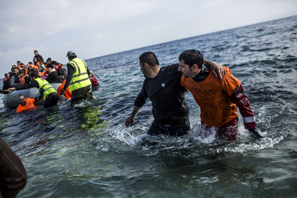 Refugees and migrants are helped by volunteers after their arrival on a dinghy from the Turkish coast to Mytilene, Lesbos, Greece, on Thursday (AP photo)