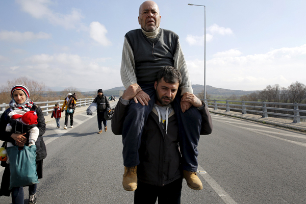 Stranded refugees walk on a motorway towards the border between Greece and the Former Yugoslav Republic of Macedonia, near the Greek village of Idomeni, on Friday (Reuters photo)