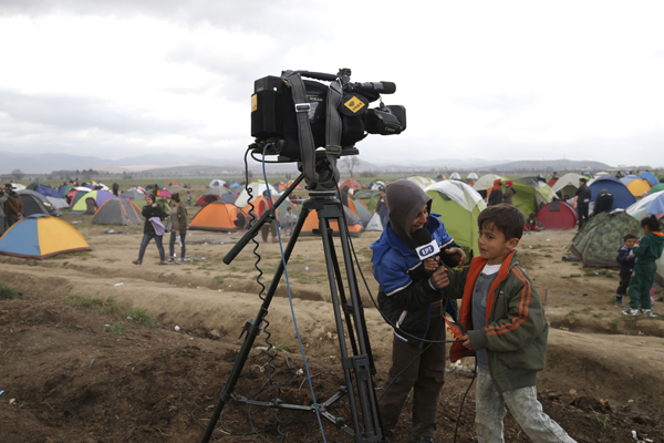 Children play with a TV camera and microphone at a makeshift camp for migrants waiting to cross the border between Greece and the former Yugoslav Republic of Macedonia, near the village of Idomeni, Greece, on Monday (Reuters photo)