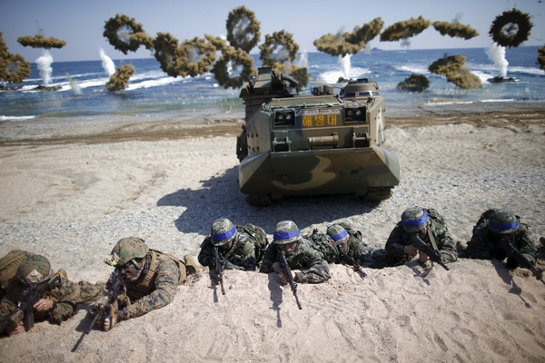 South Korean (blue headbands) and US marines take positions as amphibious assault vehicles of the South Korean Marine Corps fire smoke bombs during a US-South Korea joint landing operation drill in Pohang, South Korea, on Saturday (Reuters photo)