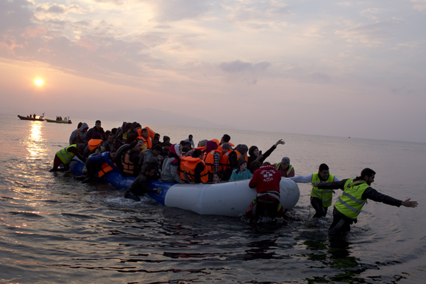 Volunteers help migrants and refugees on a dingy as they arrive at the shore of the northeastern Greek island of Lesbos, after crossing the Aegean Sea from Turkey, on Sunday (AP photo)