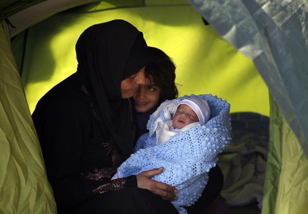 Maysa Elmohamed holds her 7-day-old baby Basel Al Sbeihi, as they rest in the makeshift refugee camp at the northern Greek border point of Idomeni, Greece, on Monday (AP photo)