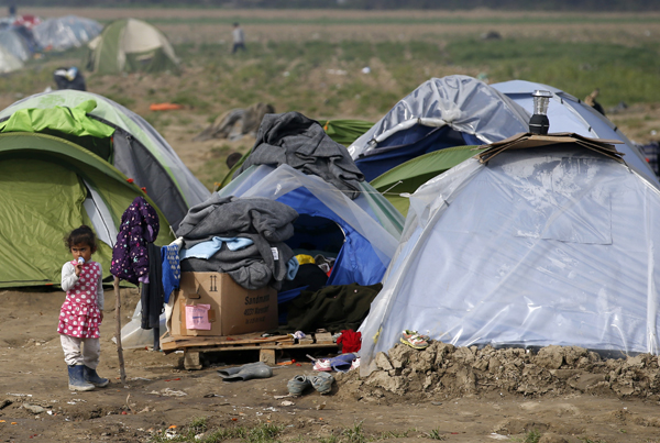 A migrant girl exits a tent in the makeshift refugee camp at the northern Greek border point of Idomeni, Greece, on Tuesday (AP photo)