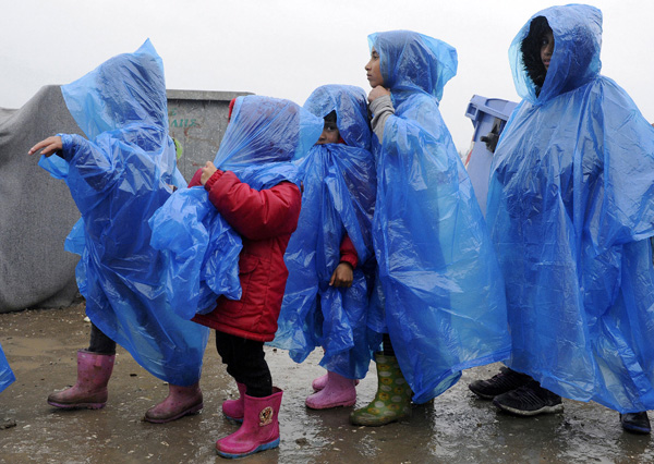 Children are covered with a plastic raincoat under heavy rainfall in a makeshift camp for refugees and migrants at the Greek-border village of Idomeni, on Wednesday (Reuters photo)