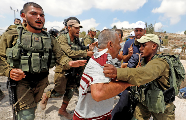 A Palestinian man argues with an Israeli soldier during a protest in the village of Ras Karkar, near Ramallah in the occupied West Bank, on Tuesday (Reuters photo)