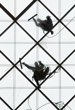 Two building cleaners clean the 27-metres-high glass ceiling of a building in Dresden, Germany, on Wednesday (AP photo)