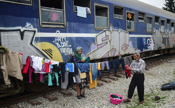 A man and his daughter hang their clothes at a makeshift camp in Idomeni on Sunday, while thousands of migrants and refugees are stranded by the Balkan border blockade (AFP photo)