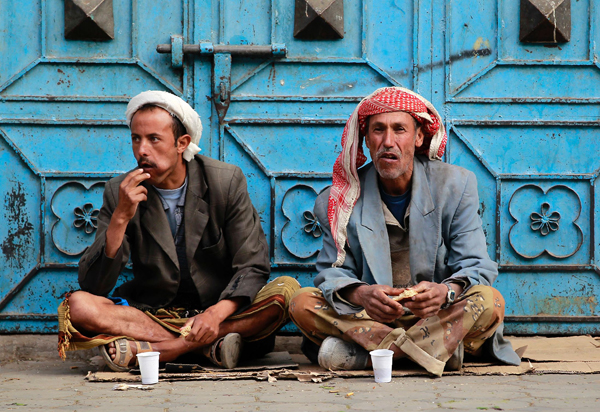 Unemployed Yemeni manual labourers eat as they wait for work offers on a sidewalk in Sanaa on Sunday (AFP photo)