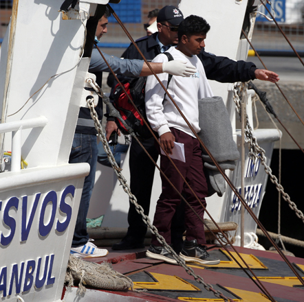 Turkish police officers provide security as migrants alight from a vessel transporting migrants from Greek island of Lesbos docked in Dikili Port, Turkey, on Monday (AP photo)