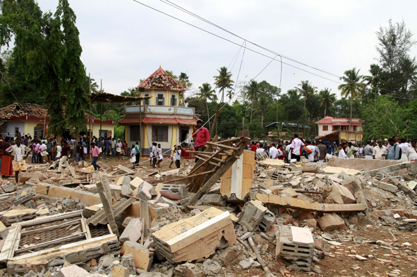 People walk past debris after a fire broke out at a temple in Kollam in the southern state of Kerala, India, on Sunday (Reuters photo)