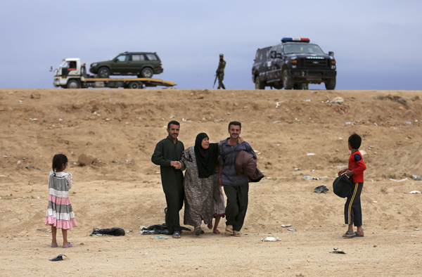 An Iraqi family flees their home as Iraqi security forces and Daesh group face off during a military operation to regain control of Heet, 140 kilometres west of Baghdad, Iraq, on Wednesday (AP photo)