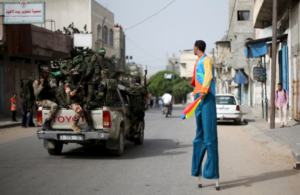 Palestinian Majed Kalluob, 24, walks with stilts as he looks at Hamas militants riding a pickup truck on a street in the northern Gaza Strip, on April 8 (Reuters photo)