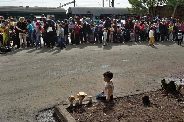 A child sits near migrants and refugees waiting in line at the railroad station in the makeshift camp at the Greek border the village of Idomeni, on Tuesday (AFP photo)