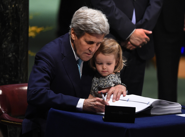 US Secretary of State John Kerry signs the book, holding his grand-daughter Isabelle Dobbs-Higginson, during the signature ceremony for the Paris Agreement at the United Nations General Assembly Hall on Friday in New York (AFP photo)
