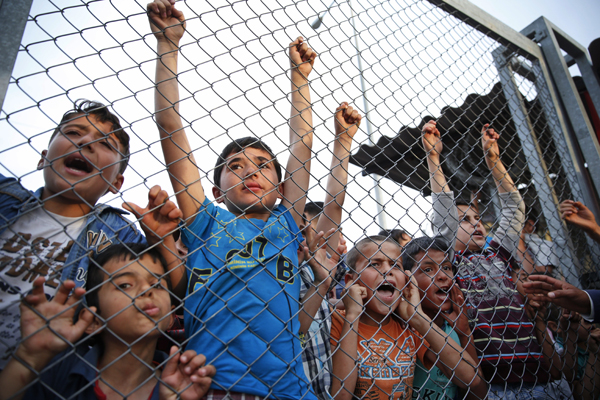 Syrian refugee children chant slogans behind a fence at the Nizip refugee camp in Gaziantep province, southeastern Turkey, following a visit by German Chancellor Angela Merkel and top European Union officials, on Saturday (AP photo)