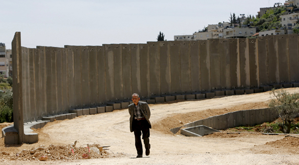 A Palestinian man walks next to a section of the Israeli separation barrier in the West Bank city of Beit Jala, near Bethlehem, on Sunday (Reuters photo)