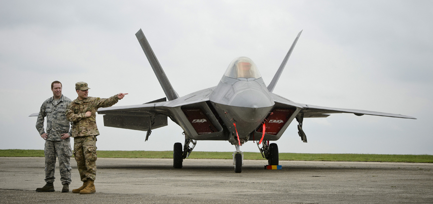 US servicemen gesture next to one of the two US Air Force F-22 Raptor fighter jets that were flown Monday to the Mihail Kogalniceanu air base, near the Black Sea port of Constanta in southeast Romania (AP photo)