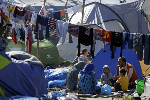 A family of migrants gather outside their tents at a makeshift camp in the northern border point of Idomeni, Greece, Wednesday (AP photo)