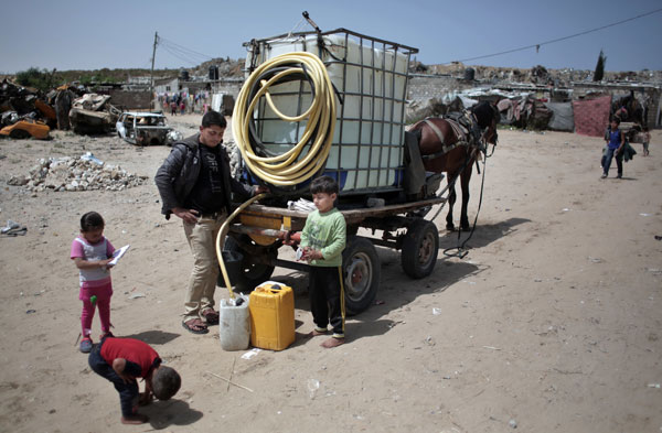 In this April 16, photo, Palestinian children fill plastic gallons with drinking water from a vendor in Khan Younis refugee camp, southern Gaza Strip. Poor sewage has damaged Gaza’s limited freshwater supplies, decimated fishing zones, and after years of neglect, is now floating northward and affecting Israel as well, where a nearby desalination plant was forced to shut down, apparently due to pollution (AP photo)