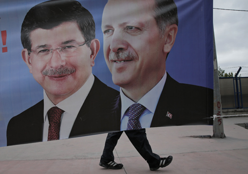 In this May 28, 2015, file photo, a man walks past a poster with pictures of Turkish Prime Minister and leader of the AKP Party Ahmet Davutoglu (left) and Turkey’s president, Recep Tayyip Erdogan, also the party’s former leader, in Istanbul (AP photo)