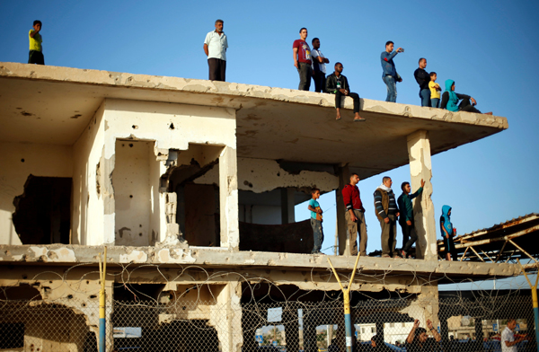 Palestinians stand atop a damaged building as they wait for their relatives to return to Gaza from Egypt through the Rafah border crossing, after it was opened by Egyptian authorities on Wednesday for two days for the first time in three months, in the Gaza Strip, on Thursday (Reuters photo)