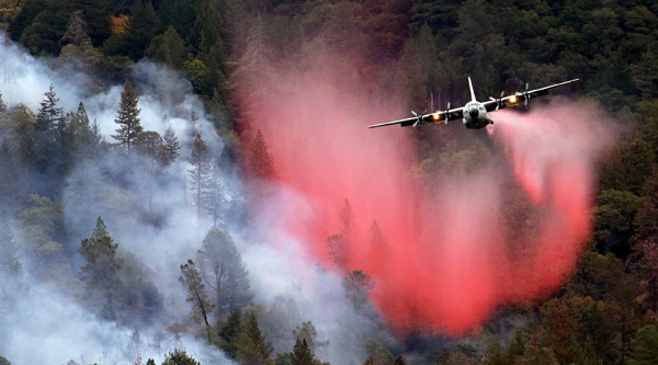 In this file photo, a firefighting plane drops a load of fire retardant over a smoldering hillside in Middletown, California (AP photo)