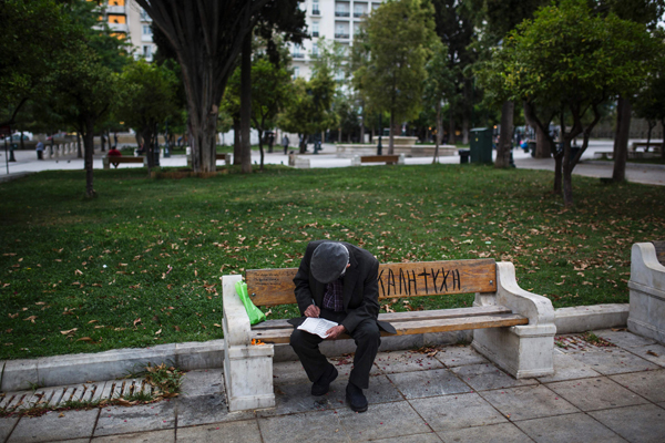 A man looks at a crossword puzzle as he sits on bench in Syntagma Square in Athens on Sunday (AFP photo)