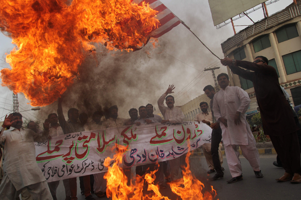 A Pakistani demonstrator holds a burning US flag as others shout slogans during a protest  in Multan on Tuesday (AFP photo)