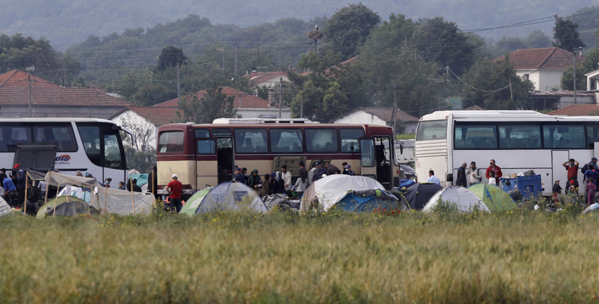 Refugees and migrants board buses to leave the makeshift refugee camp during a police operation at the Greek-Macedonian border near the northern Greek village of Idomeni, photographed from the Macedonian side of the border, on Tuesday (AP photo)