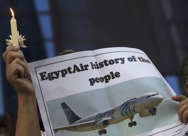 An Egyptian journalist holds a candle and a poster supporting EgyptAir during a candlelight vigil for the victims of EgyptAir flight 804 in front of the Journalists’ Syndicate in Cairo, Egypt, on Tuesday (AP photo)