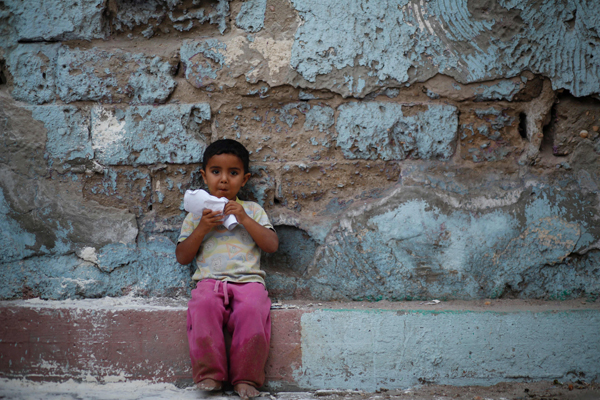  A Palestinian boy eats paper-wrapped corn next to his house in Gaza City, on Wednesday (AFP photo)
