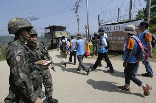 South Korean activists march along the military wire fences as South Korean army soldiers stand guard during 2016 Women Walk for Korean Peace at the Imjingak Pavilion near the border village of Panmunjom in Paju, South Korea, on Saturday (AP photo)