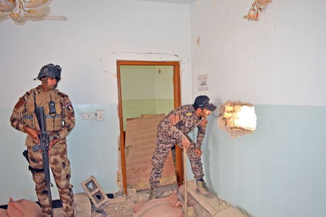 Iraqi security forces personnel inspect a house south of Fallujah, Iraq, on Monday (Reuters photo)