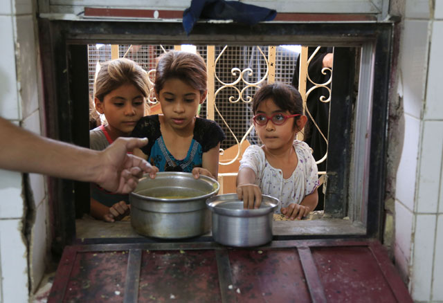 Girls receive free food for their families distributed foriftar, the evening meal breaking the Ramadan fast, at the Abdul Khader Al Kilani Mosque in Baghdad, Iraq, Wednesday (AP photo)
